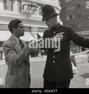 Anfang der 1950er Jahre, London, England, 'so, Herr'...historisches Bild, das einen uniformierten britischen Polizeibeamten zeigt, der einem neu eingetroffenen ausländischen männlichen Besucher mit Wegbeschreibungen hilft. Stockfoto