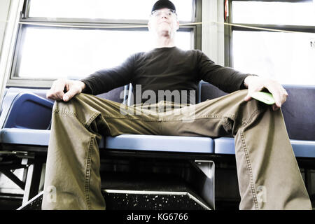 Mann in Beschlag nehmen mehr als einen Sitz (man verbreiten) auf New York City Bus, NYC, USA Stockfoto