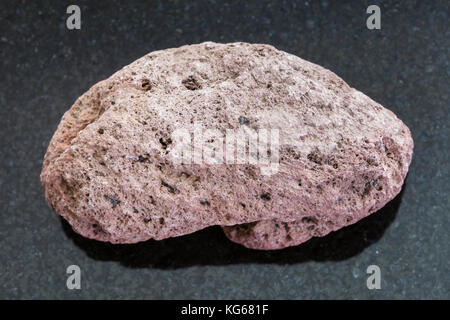 Makroaufnahmen von natürlichen Mineralgestein Muster - rot Bimsstein Kiesel auf dunklem Granit Hintergrund aus Sizilien Stockfoto