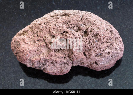 Makroaufnahmen von natürlichen Mineralgestein Muster - rot Bimsstein auf dunklem Granit Hintergrund aus Sizilien Stockfoto