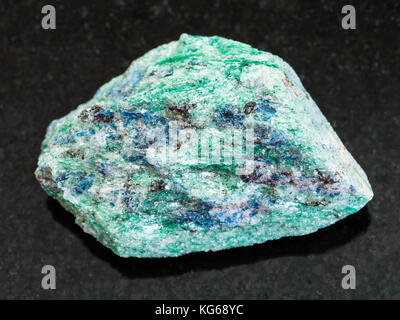 Makroaufnahmen von natürlichen Mineralgestein Muster - raw fuchsite (Chrom Glimmer) Stein auf dunklem Granit Hintergrund aus hizovaara, Republik Karelien in r Stockfoto