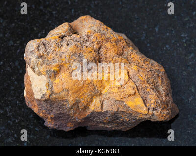 Makroaufnahmen von natürlichen Mineralgestein Muster - raw Limonit Stein auf dunklem Granit Hintergrund aus olkhinskoye Mine, Irkutsk Region, Russland Stockfoto