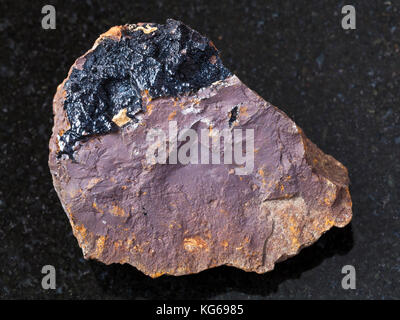 Makroaufnahmen von natürlichen Mineralgestein Muster - konkretisierung von goethit Aggregaten auf limonit Stein auf dunklem Granit Hintergrund aus olkhinskoye Mine Stockfoto