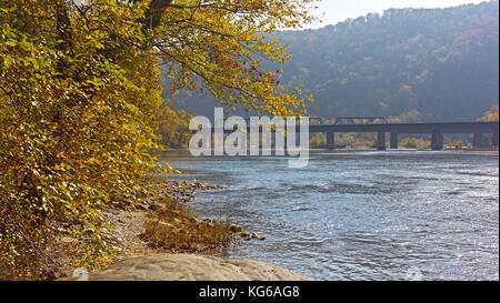 Goldener Herbst am Potomac River in der Nähe von Harpers Ferry historische Stadt. Eisenbahnbrücke, die Berge und den Fluss Banken im Herbst, West Virginia, USA. Stockfoto