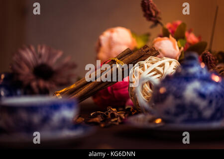 Gemahlener Zimt, Zimtstangen, mit einem Tablett mit einem Bogen auf einem floral background im rustikalen Stil verbunden. Selektive konzentrieren. Essen Konzept. Jahrgang zu Stockfoto