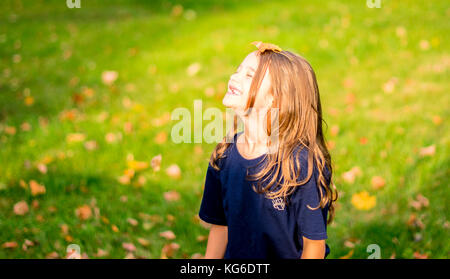 Mädchen spielen mit Herbstlaub Stockfoto