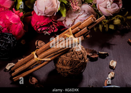 Gemahlener Zimt, Zimtstangen, mit einem Tablett mit einem Bogen auf einem floral background im rustikalen Stil verbunden. Selektive konzentrieren. Essen Konzept. Jahrgang zu Stockfoto