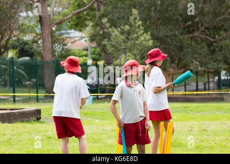 Australische Schulen Kinder spielen Cricketsport in der Schule, Sydney, Australien tragen rot-weiße Schulsportuniform Stockfoto