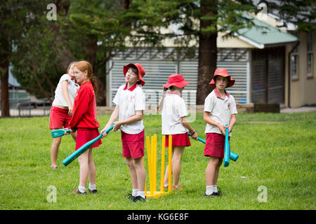 Australische Schulen Junge und Mädchen Kinder spielen Cricket-Sport in der Schule, Sydney, Australien tragen rot-weiße Schuluniform Stockfoto