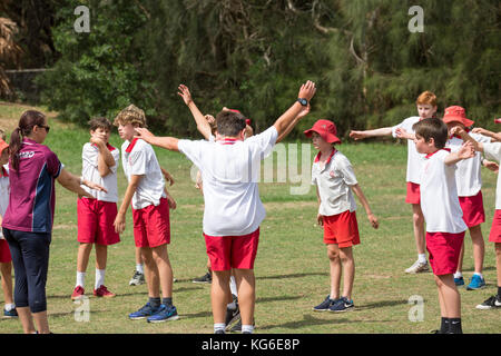 Australische Schulen Kinder, die Sport in der Schule spielen, Sydney, Australien, beaufsichtigt von Sportlehrerin der Schule Stockfoto