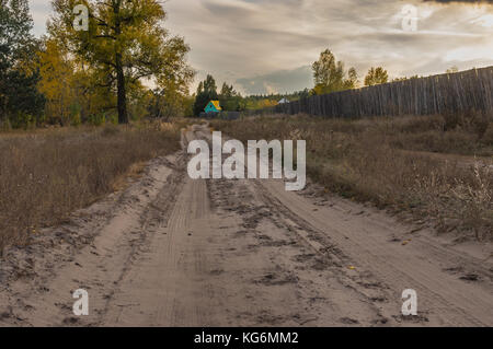 Landschaft mit sandigen Straße, die zu kleinen grün-gelben Haus, stehend auf einem Wald Seite Stockfoto