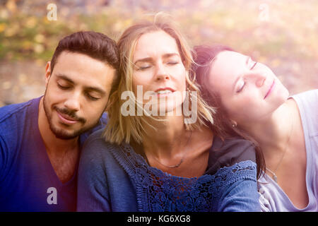 Portrait von drei Freunden draußen sitzen und entspannen in der Sonne Stockfoto