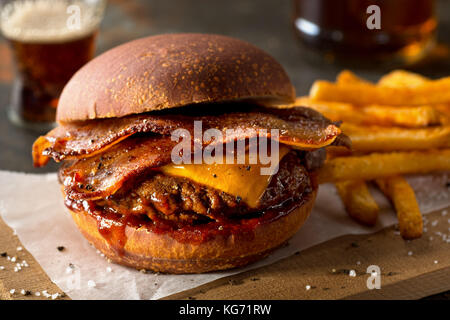 Ein leckeres Pub Stil bacon Cheeseburger mit Barbecue Sauce und Pommes Frites. Stockfoto