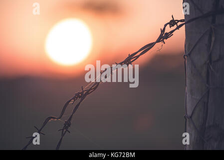 Sonnenuntergang hinter dem Ende der ein Stacheldrahtzaun. Stockfoto