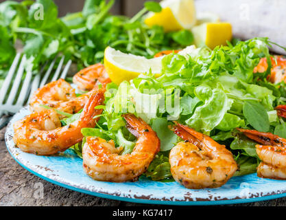 Meeresfrüchte Garnelen Garnelen. Srimp Salat Salat auf blaue Platte mit Zitrone Rosmarin Rucola auf Holz rustikale Hintergrund. Gesunde Ernährung oder Diät Konzept. Stockfoto