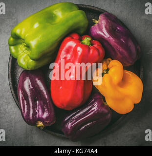 Viele farbige Paprika ppurple, Rot, Grün, Gelb auf Schwarz platte Tabelle, grauem Schiefer Hintergrund Stockfoto