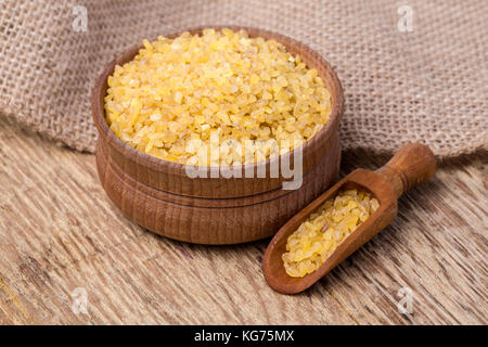 Raw Bulgur (auf Holz- Hintergrund) als detaillierte Nahaufnahme Stockfoto