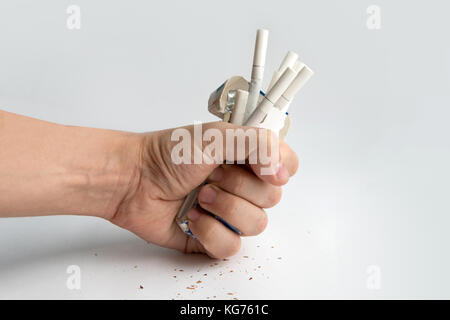 Ein Kerl drückt eine Packung Zigaretten auf weißem Hintergrund. des Menschen Hand Zerkleinern von Zigaretten zu rauchen zu beendigen. Stockfoto