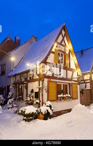 Eine Gasse mit Fachwerkhäusern und Weihnachten Lichter in der Nacht bei Schneefall in Haines, Edenkoben, Deutschland. Stockfoto