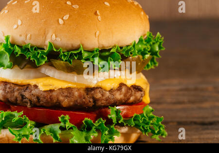 Helle saftige leckere Burger mit einem Schnitzel, Käse, marinierten Gurken, Tomaten und Speck in die Hände eines Mädchens, ein Mädchen in spezielle Handschuhe für die Bu Stockfoto