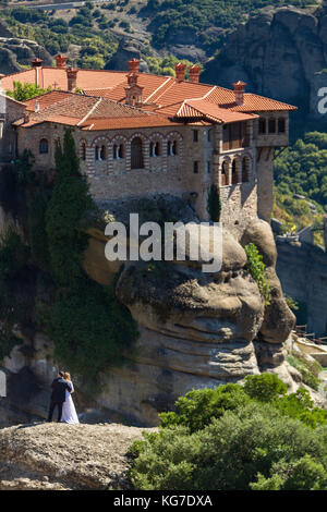 Meteora, Griechenland - 9 Oktober, 2017: Der Bräutigam, die Braut auf einem Felsen von Meteora varlaam mit Kloster im Hintergrund. Aufnahme im Hochformat Stockfoto