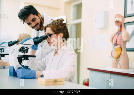 Junge Wissenschaftler durch Mikroskop im Labor auf der Suche Stockfoto