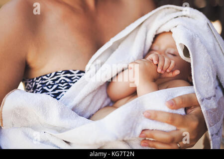 Junge Mutter, die ihr neugeborenes Baby schlafen Stockfoto