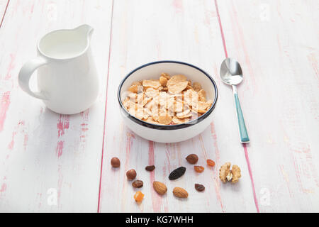 Schüssel Cornflakes und Milch, Haselnuss, chemische Aprikose, Nussbaum und Muttern auf Holz- Hintergrund, Nahaufnahme Stockfoto