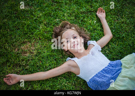 Lächelnde Mädchen, die auf dem Gras mit glücklichen unbeschwerten Ausdruck - Begriff der Freiheit in der Kindheit Stockfoto