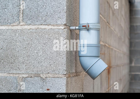 Industrielle Wasser ablassen PVC-Rohr mit Betonklotz im Hintergrund Stockfoto