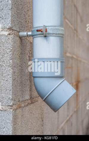 Industrielle Wasser ablassen PVC-Rohr mit Betonklotz im Hintergrund Stockfoto