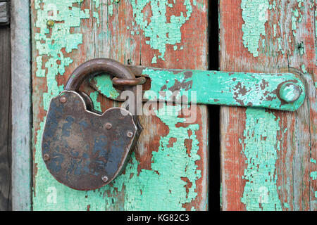Alten rostigen Vorhängeschloss hängen an eine alte Holztür. Sicherheitskonzept: offenes Vorhängeschloss auf Holz- wand. Stockfoto