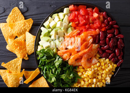 Salat mit Garnelen und Gemüse und Nachos close-up auf dem Tisch. horizontal oben Ansicht von oben Stockfoto