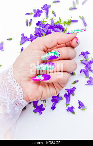 Hand mit Nägeln wieder aufgebaut und dekoriert mit bunten Blumen blaue und weiße Blumen auf weißem Hintergrund bringen, schöne Neuheit für Frühling und Sommer Stockfoto