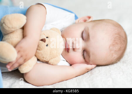 Schlafendes Baby im Bett, ein Teddybär. Stockfoto