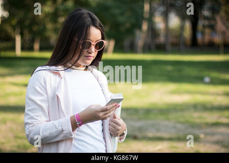 Junges Mädchen mit Smartphone im Freien in einem Park Stockfoto