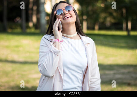 Junge Mädchen reden auf dem Smartphone fröhlich im Freien in einem Park Stockfoto