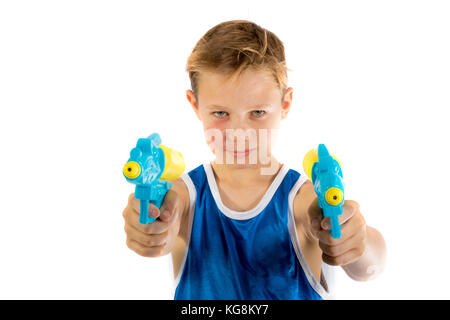 Pre-teen Junge spielt mit Wasserpistolen auf weißem Hintergrund Stockfoto