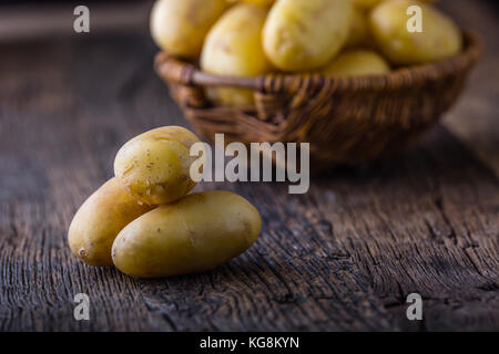 Frische rohe Kartoffeln in Korb auf Eiche rustikal. Stockfoto