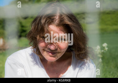 Offen Porträt einer schönen Brünette, mittleren Alters Frau - Sommerbrise weht in ihr Haar. Much Wenlock, Shropshire, Großbritannien Stockfoto