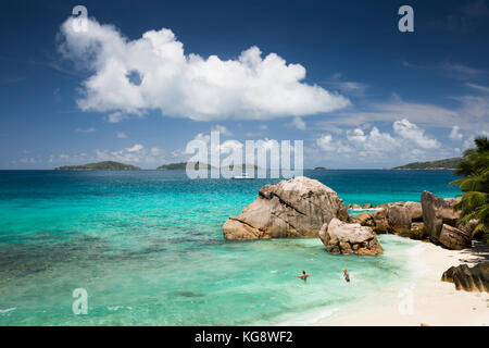 Die Seychellen, La Digue, Anse Patates, Touristen in Meer geschützt hinter riesigen Granitfelsen Stockfoto