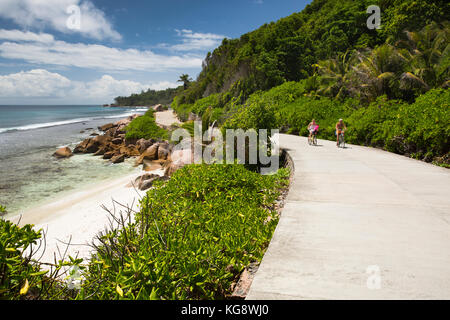 Die Seychellen, La Digue, Anse Die, zwei ältere Touristen Radfahren auf leere East Coast Road Stockfoto