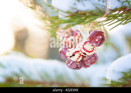 Weihnachten bunte vintage Glocken auf den Ästen eines schneebedeckten Baumes. getönt Stockfoto