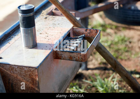 Eine Nahaufnahme eines Kaffeebecher sitzen neben hydraulischen Maschinen Steuerhebel. Stockfoto