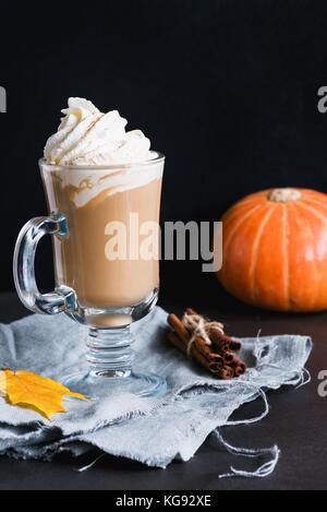 Pumpkin spice Latte oder Kaffee mit Sahne, Zimt und Marshmallows in Glas mug über schwarzen Hintergrund. Vertikale, kopieren Platz für Text Stockfoto