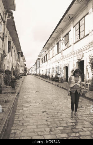 Vigan, Philippinen - 17. Juni 2009: Frau Spaziergänge in der schönen kolonialen Straße mit Kopfsteinpflaster von Vigan in Nord Luzon, Philippinen. Schwarz und Weiß. Stockfoto