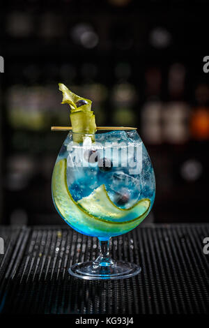 Blue Gin Tonic mit Gurke auf der Theke serviert. Stockfoto