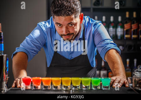 Barkeeper posiert mit seinem Rainbow cocktail Kreation Stockfoto