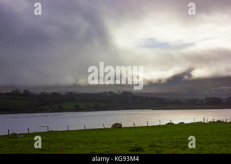 Blick auf das Meer in Irland regen Wolken über die Berge und blauer Himmel, Sonne, aus der Cloud grüne Felder Fluss Stockfoto
