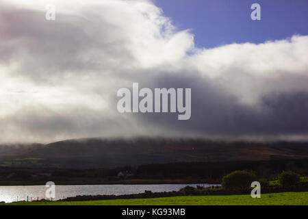 Blick auf das Meer in Irland regen Wolken über die Berge und blauer Himmel, Sonne, aus der Cloud grüne Felder Fluss Stockfoto